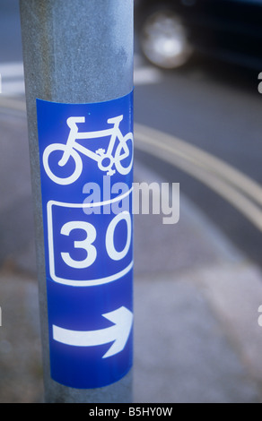 Close up of stick-sur bleu et blanc signe sur pole indiquant cycle régional numéro de réseau avec black car tournant à la jonction Banque D'Images