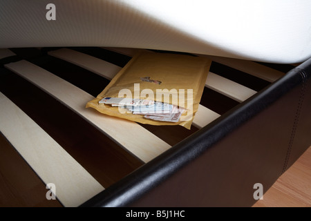 Liasse de 50 20 et 10 euros dans une enveloppe de trésorerie notes fourré sous le matelas d'un lit Banque D'Images