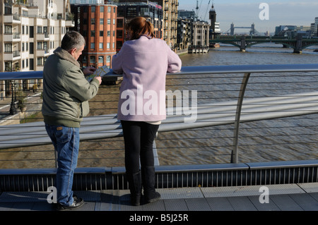 Un couple reading a map sur le Millenium Bridge, London, UK Banque D'Images