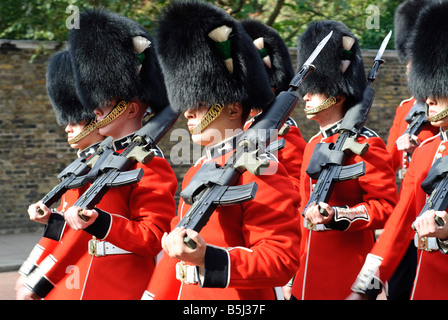 Grenadier Guards Parade Buckingham Palace Londres | LONDRES, Royaume-Uni — Rows of Foot Guards marche épaule contre épaule, baïonnettes fixes et coiffes en peau d'ours brillantes avec des chaînes de menton dorées, lors d'une procession de relève de la garde. L'uniforme écarlate et noir, inchangé dans l'essentiel depuis des générations, identifie les soldats comme des membres des régiments de garde cérémonielle de la Division de la maison. Banque D'Images