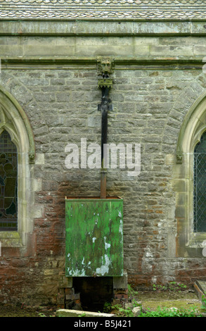 Un vieux tuyau de drainage sculptés en pierre se corrode sur le côté d'une église dans le Derbyshire, Royaume-Uni. Banque D'Images