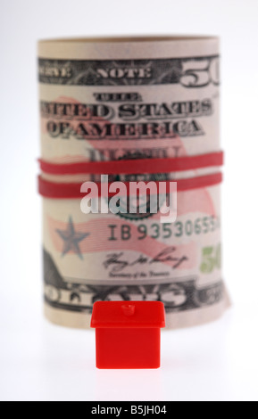 Une maison rouge sur l'avant d'une liasse de 50 billets de banque en dollars usa paiement lié à un rouleau avec bande élastique Banque D'Images