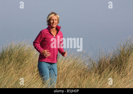 Jeune femme blonde à l'extérieur. La course à travers l'herbe haute. Banque D'Images