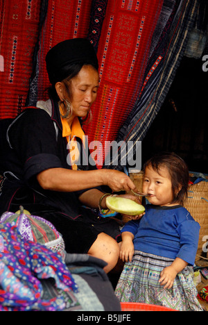 Femme Hmong noir nourrir son enfant dans la zone du marché Sapa dans le nord du Viet Nam Banque D'Images