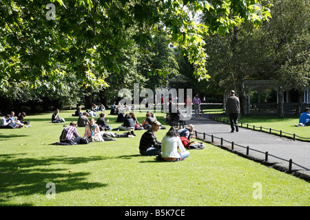 Les gens se détendre sur une chaude journée à St Stephens Green Dublin 2 Irlande Banque D'Images