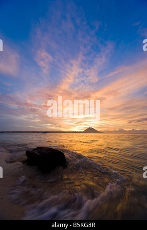 Coucher du soleil tropical - vagues roulant sur la plage peut être vu dans l'avant-plan. Banque D'Images