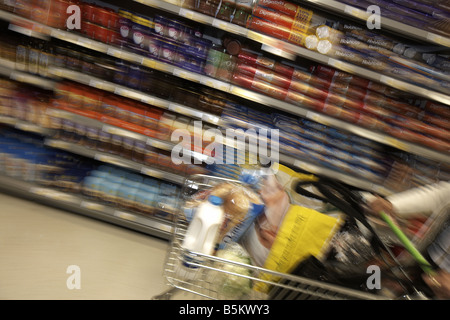 Chariot de supermarché en mouvement rapide avec la nourriture empilés par fringant shop Banque D'Images