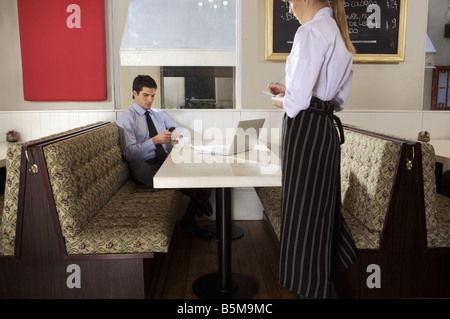 L'homme à la recherche d'un cellulaire tout en buvant un café. Banque D'Images