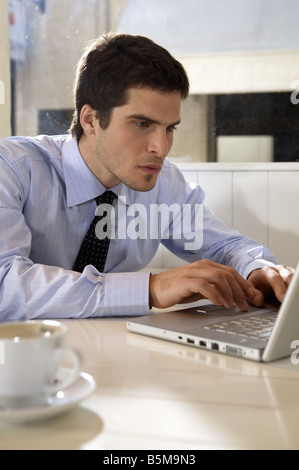 L'homme travaillant avec un ordinateur portable dans un restaurant. Banque D'Images