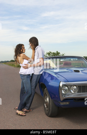 Un couple appuyé contre une voiture Banque D'Images