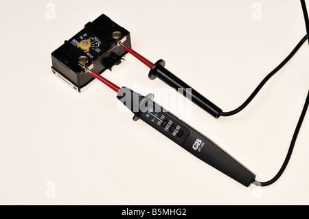 Testeur d'alimentation électrique AC avec sondes sur le thermostat du chauffe-eau sur fond blanc Banque D'Images