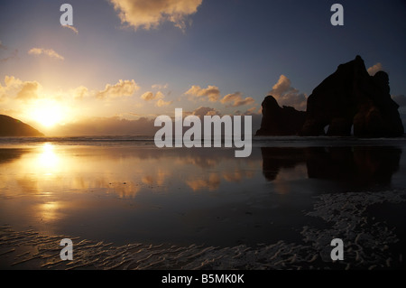 Îles d'Archway reflétée dans les sables humides de Wharariki Beach au coucher du soleil, près du cap Farewell NW Nelson Region ile sud Nouvelle Zelande Banque D'Images