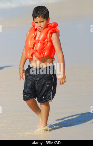 Un garçon marche dans les sables de la plage de Punta Cana, République dominicaine une Republicwearing gilet de sauvetage. Banque D'Images