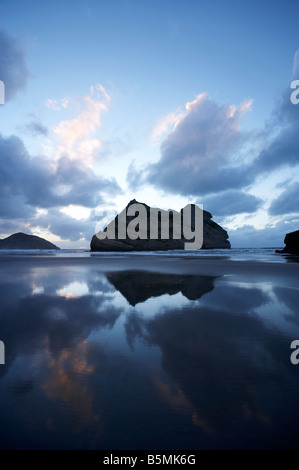 Îles d'Archway reflétée dans les sables humides de Wharariki Beach au crépuscule près de Cape Farewell NW elson Région ile sud Nouvelle Zelande Banque D'Images