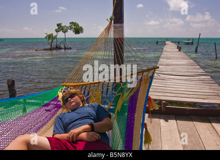 CAYE CAULKER, BELIZE - garçon repose dans un hamac sur un quai au bord de la mer des Caraïbes. M. Banque D'Images