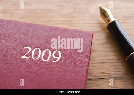 2009 Agenda en cuir rouge et stylo sur le comptoir en bois Banque D'Images