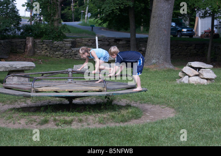 Deux jeunes enfants tournant sur un manège à l'été dans le pays. Banque D'Images