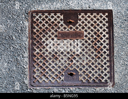 Avec l'éclosion d'égout métallique carré rouille légère sur la surface du béton Banque D'Images