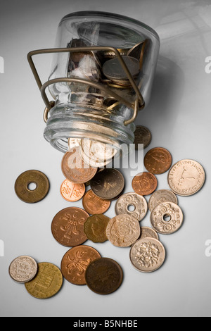 Meubles anciens et obsolètes des crédits déversés par un récipient en verre avec fond blanc Banque D'Images