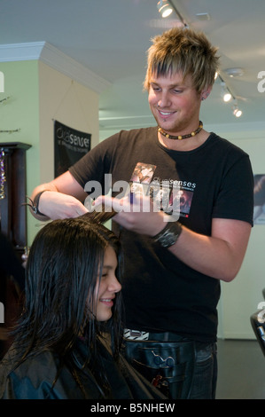 Un adolescent ayant fait couper les cheveux par un coiffeur dans un salon de coiffure Banque D'Images