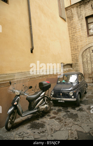 Vieille voiture Fiat 500 noire et scooter garé en bas petite rue étroite à Florence, Italie. Banque D'Images