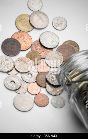 Meubles anciens et obsolètes des crédits déversés par un récipient en verre avec fond blanc Banque D'Images