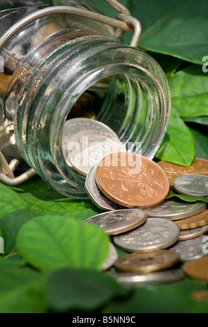 Pièces antiques déversés par un récipient en verre sur Vert feuilles Banque D'Images