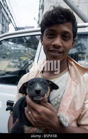 Un jeune homme tenant un petit chien Dhaka Banque D'Images