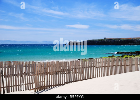 Plage de sable fin de Tarifa avec clôtures à sable en bois contre le ciel bleu et la mer bleu-vert Banque D'Images