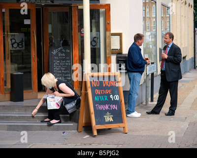 Deux hommes et une fille potable fumeurs à l'extérieur d'un pub London UK Banque D'Images