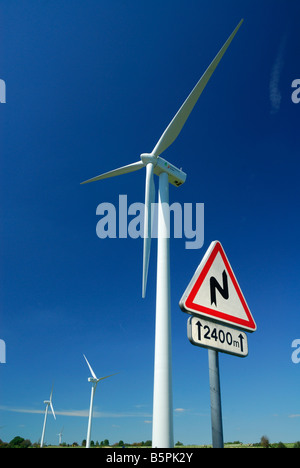 Avant de signer les courbes de la route près d'un parc éolien sur ciel bleu - France Banque D'Images