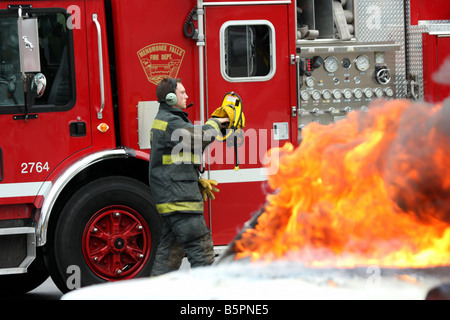 Un pompier FTU se préparer à l'avant d'un camion de pompiers pour combattre le feu Banque D'Images