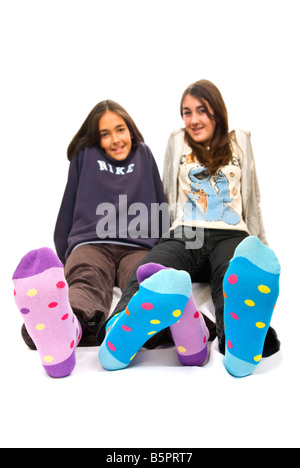 Close up vertical de deux adolescentes pieds aux couleurs de polka dot Winter socks sur sur un fond blanc. Banque D'Images