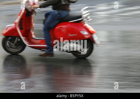 Personne en cyclomoteur scooter Vespa rouge pluie à Rome Italie Banque D'Images