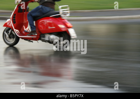 Personne en cyclomoteur scooter Vespa rouge pluie à Rome Italie Banque D'Images