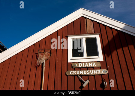 Cabane de pêcheurs en bois rouge à côté du port dans le village de Grundsund sur la côte de Bohuslan en Suède Banque D'Images