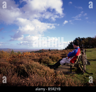 Cycliste assis sur un banc. Le gibet Hill, Hindhead, Surrey, Angleterre, Royaume-Uni. Banque D'Images