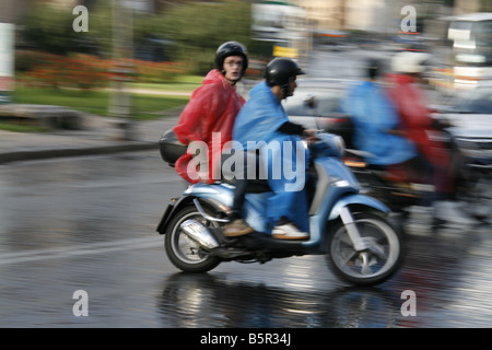 Groupe de jeunes touristes circonscription louer Location scooters cyclomoteurs en pluie dans Rome Italie Banque D'Images