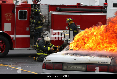 Trois pompiers l'obtention d'un prêt d'un hoseline camion à incendie lors d'un incendie lors d'une démonstration de la sécurité incendie Banque D'Images