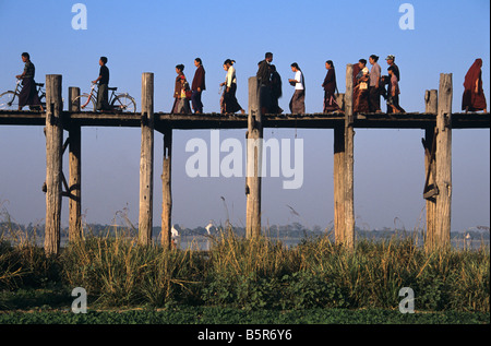 Piétons et cyclistes birmans traverser le pont de U Bein, le plus long pont en teck du monde, à Amarapura, près de Mandalay, Birmanie Banque D'Images