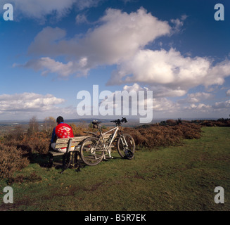 Cycliste assis sur un banc. Le gibet Hill, Hindhead, Surrey, Angleterre, Royaume-Uni. Banque D'Images