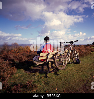 Cycliste assis sur un banc. Le gibet Hill, Hindhead, Surrey, Angleterre, Royaume-Uni. Banque D'Images