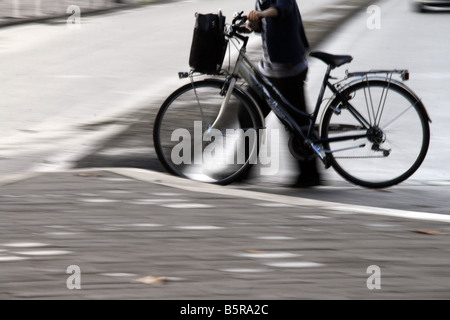 Jeune femme en poussant le vélo sur rue en ville Banque D'Images