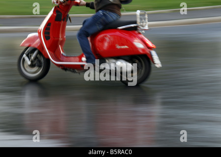 Personne en cyclomoteur scooter Vespa rouge pluie à Rome Italie Banque D'Images