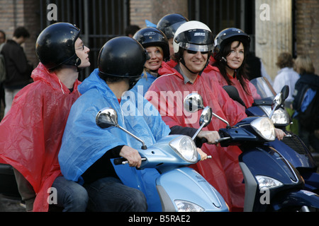Groupe de jeunes touristes circonscription louer Location scooters cyclomoteurs en pluie dans Rome Italie Banque D'Images