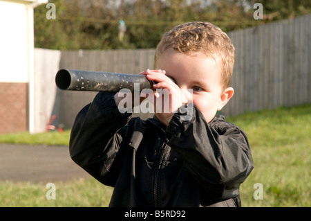 Les jeunes enfants en crèche garderie garçon à l'aide d'un vieux tube comme un télescope Banque D'Images