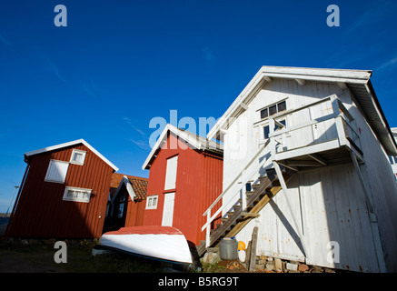 Les cabanes de pêcheurs en bois ont peint le rouge et le blanc dans le port du village de Grundsund sur la côte suédoise de Bohuslan Banque D'Images