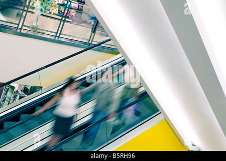 Couple floue sur un escalator à un centre commercial Banque D'Images