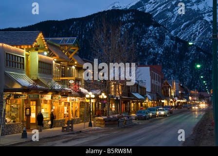 Boutiques le long de l'avenue Banff, au crépuscule, la ville de Banff, Banff National Park, Alberta, Canada. Banque D'Images