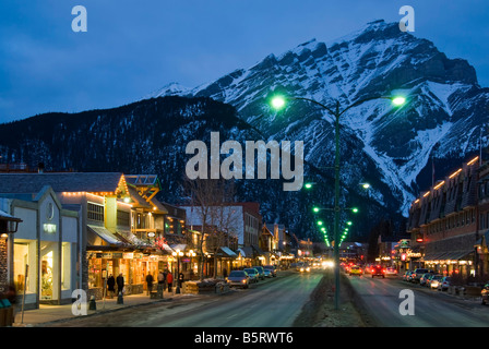 Boutiques le long de l'avenue Banff, au crépuscule, la ville de Banff, Banff National Park, Alberta, Canada. Banque D'Images
